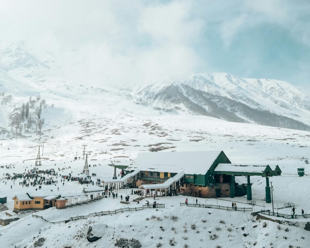Aerial view of Gulmarg resort with snowy mountains, perfect winter travel destination.