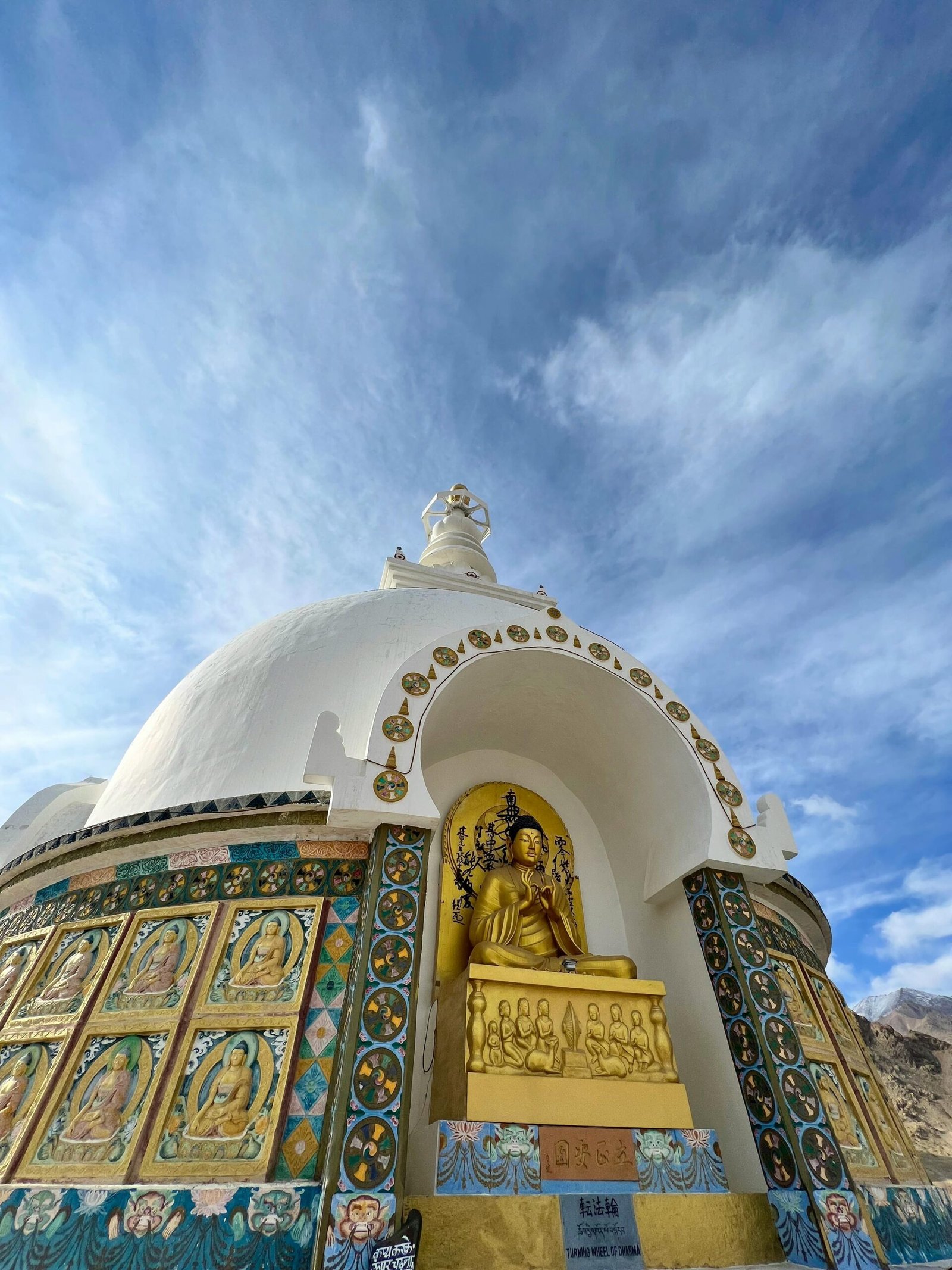 Majestic view of Shanti Stupa in Leh, featuring intricate artwork and a serene dome under clear blue skies.