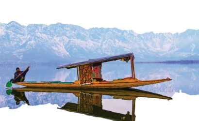 A vibrant shikara on Dal Lake with the stunning Himalayan backdrop, perfect for travel exploration.